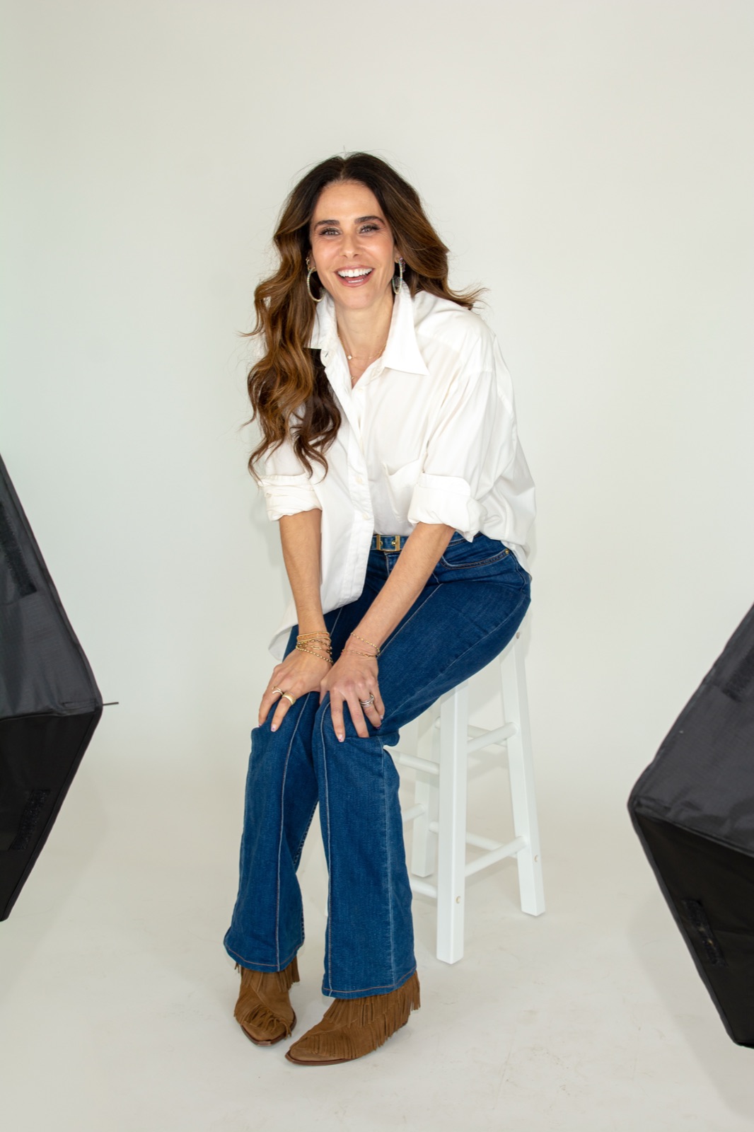 Cassie Blakely seated on a stool in a white shirt and jeans